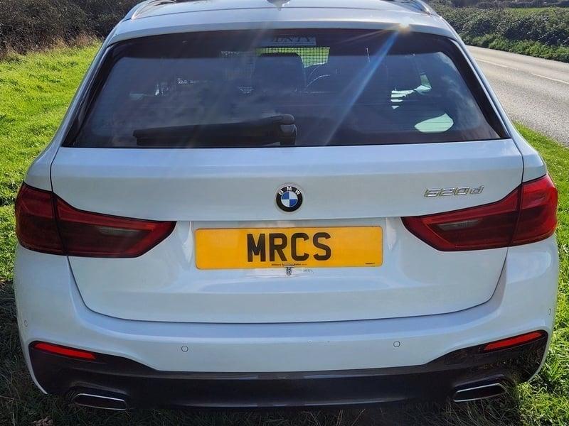The back of a white BMW 5 Series Estate car