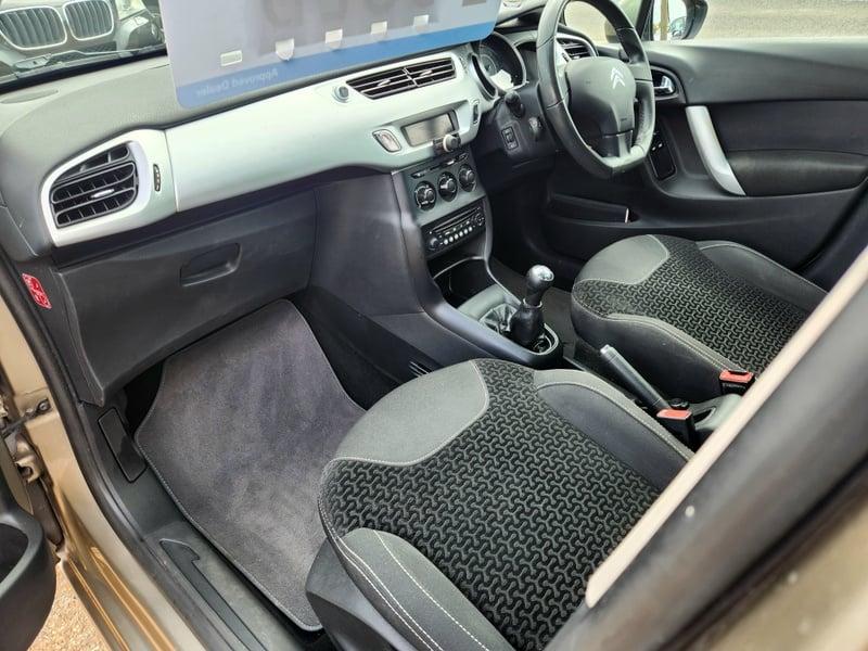 The front seats, steering wheel, and controls viewed from the left side of a gold Citroen C3 VTR+