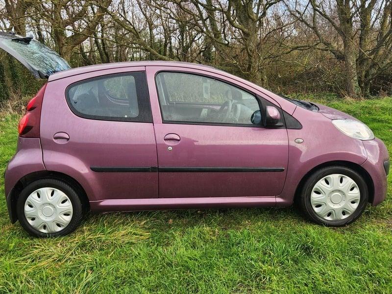A plum purple Peugeot 107 viewed from the outside right