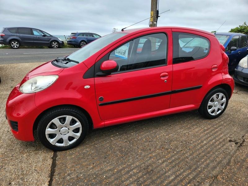 A red Peugeot 107 Urban viewed from the outside left