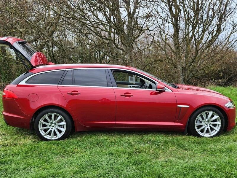 An odyssey red metallic Jaguar XF Sportback viewed from the outside right