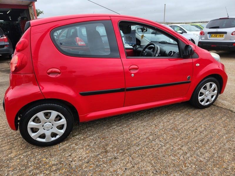 A red Peugeot 107 Urban viewed from the outside right