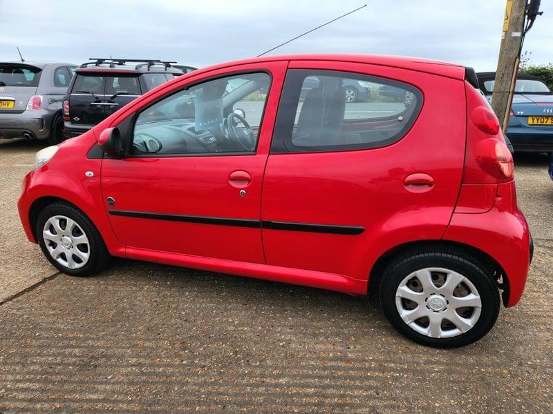 A red Peugeot 107 Urban viewed from the outside left
