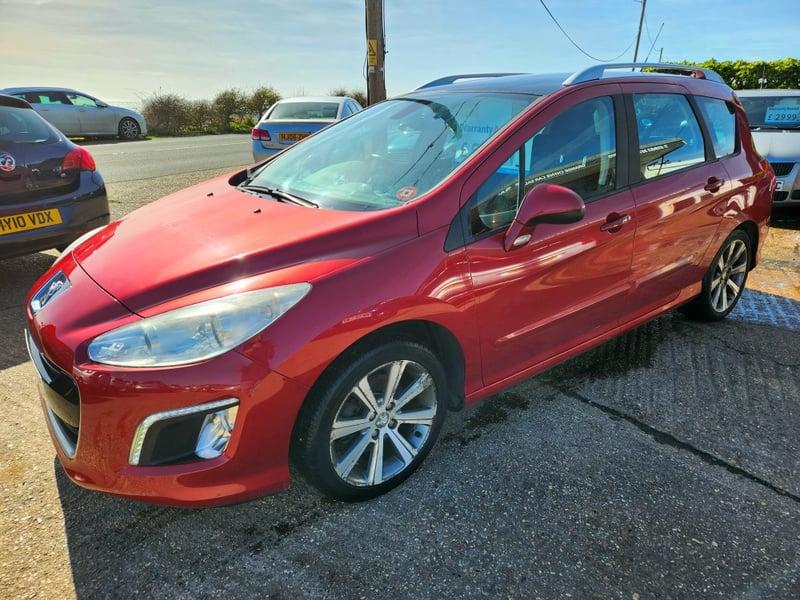 A red Peugeot 308 SW Active HDi viewed from the left side front corner