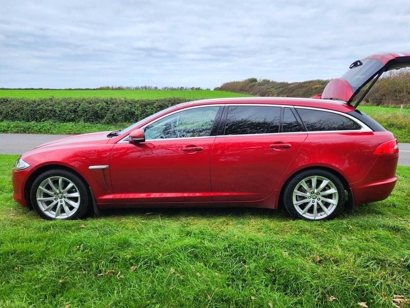 An odyssey red metallic Jaguar XF Sportback viewed from the outside left