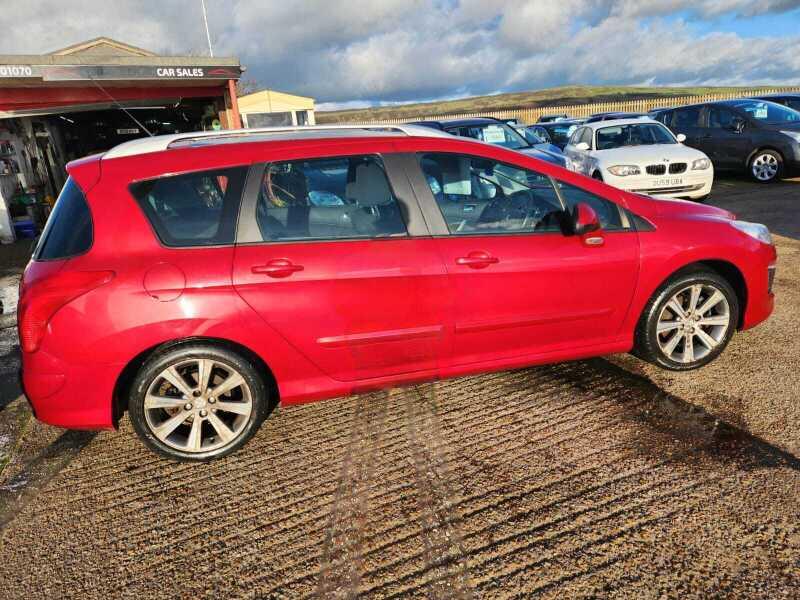 A red Peugeot 308 SW Active HDi viewed from the right side