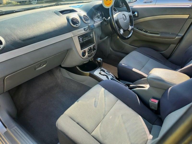 The front seats, steering wheel, and controls of a Chevrolet Lacetti 1.8 SX from the left side