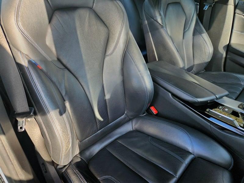 The front seats and center control console of a BMW 5 Series Touring 520d M Sport Auto from the right side