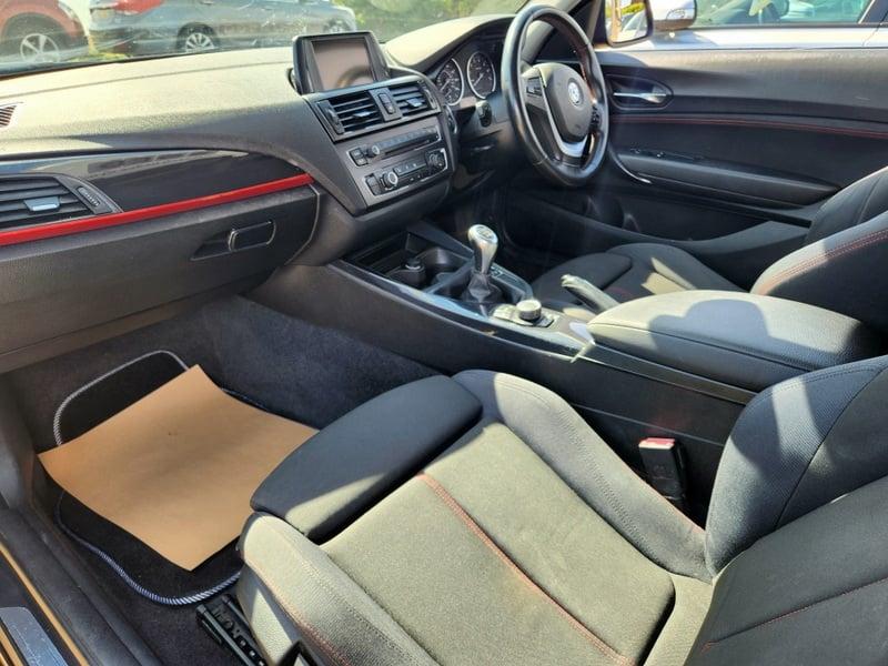 The front seats, steering wheel, and controls of a BMW 1 Series 116i Sport from the left