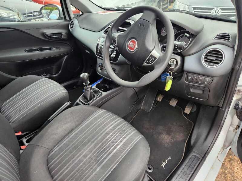 The front seats, steering wheel, and controls of a Fiat Punto Evo from the right side.