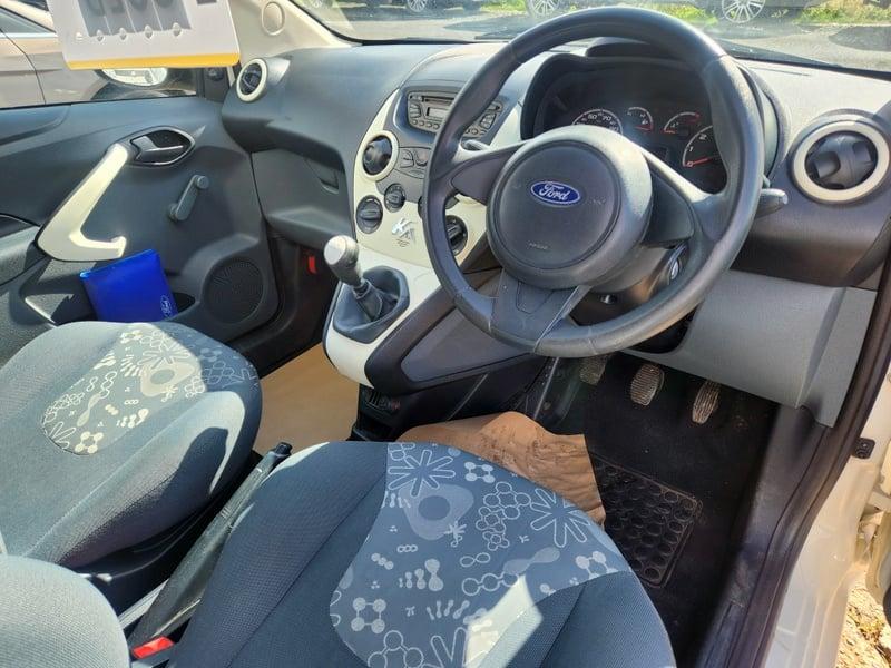 The front seats, steering wheel, and controls of a right-hand drive Frozen White Solid Ford Ka Studio, from the right side.