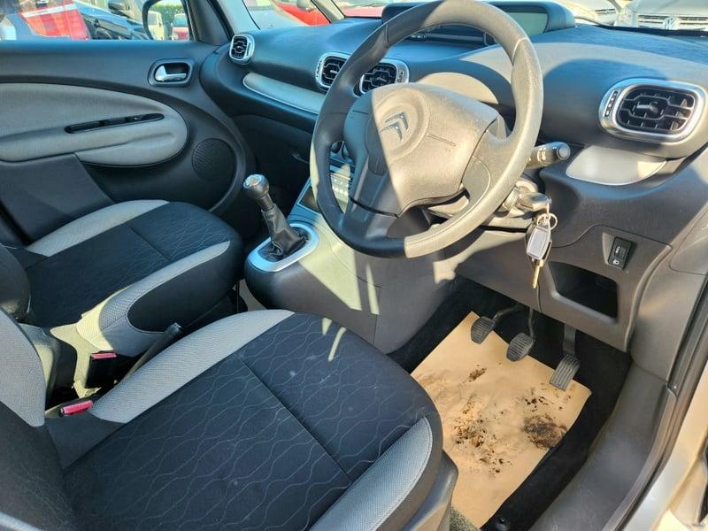 The front seats, steering wheel, and controls of a Citroen C3 Picasso 1.4 from the right