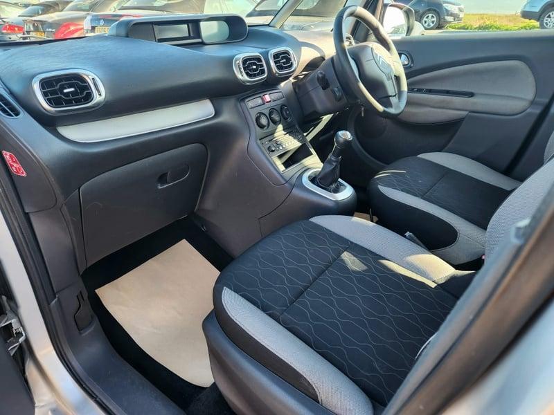 The front seats, steering wheel, and controls of a right-hand drive Citroen C3 Picasso 1.4, from the left side.