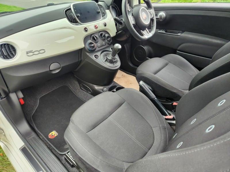 The front seats, steering wheel, and controls of a Fiat Abarth 1.4 from the left side.