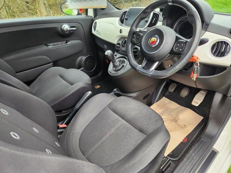The front seats, steering wheel, and controls of a Fiat Abarth 1.4 from the right side.