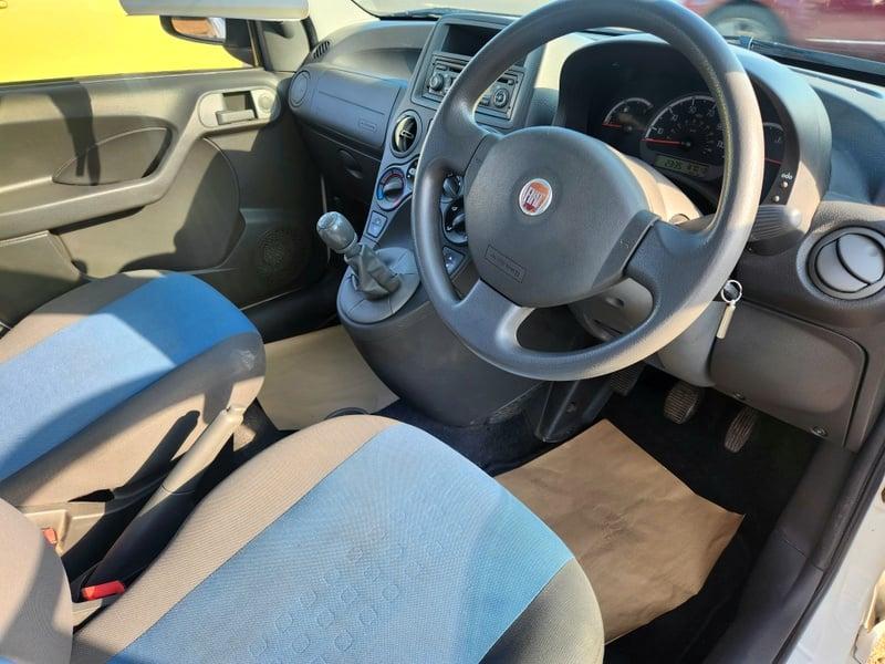 The front seats, steering wheel, and controls of a white Fiat Panda Active, from the right.