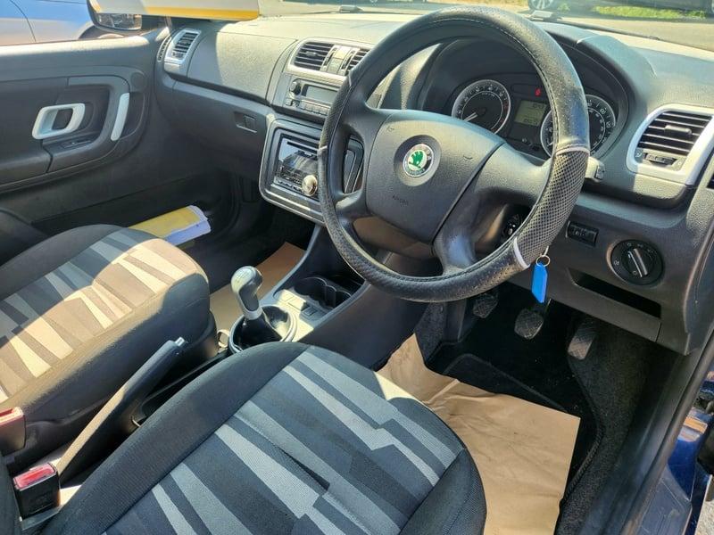 The front seats, steering wheel, and controls on a Ocean Pacific Blue Skoda Fabia 2 Blueline, viewed from the right side.