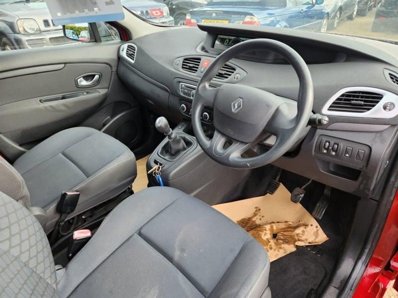 The front seats, steering wheel, and controls on a red Renault Scenic 1.4 TCE Expression, viewed from the right side.