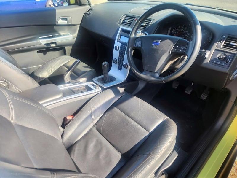 The front seats, steering wheel, and controls on a Lime Yellow Volvo, C30 SE LUX, viewed from the right side.