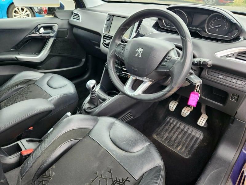 The front seats, steering wheel, and controls on a blue Peugeot 208 1.6 e-HDi Feline, viewed from the right side.