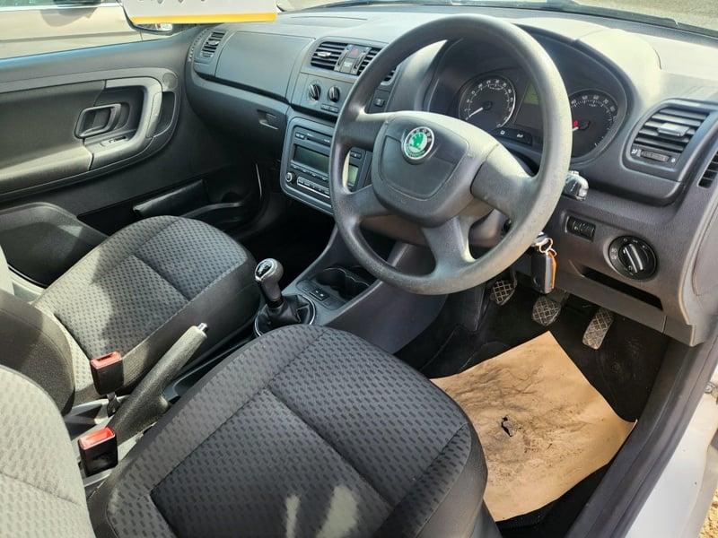 The front seats, steering wheel, and controls on a white Skoda Fabia Greenline TDI CR, viewed from the right side.