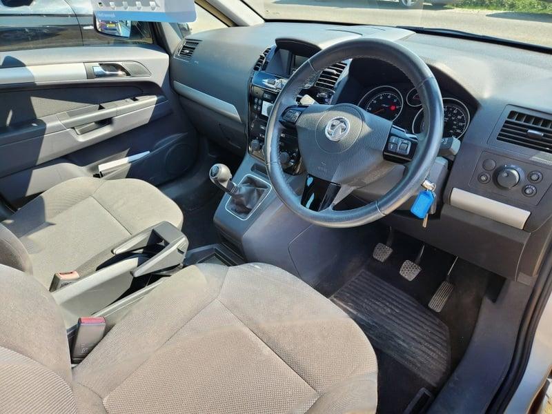 The front seats, steering wheel, and controls on a silver Vauxhall Zafira 1.8i Exclusiv, viewed from the right side.