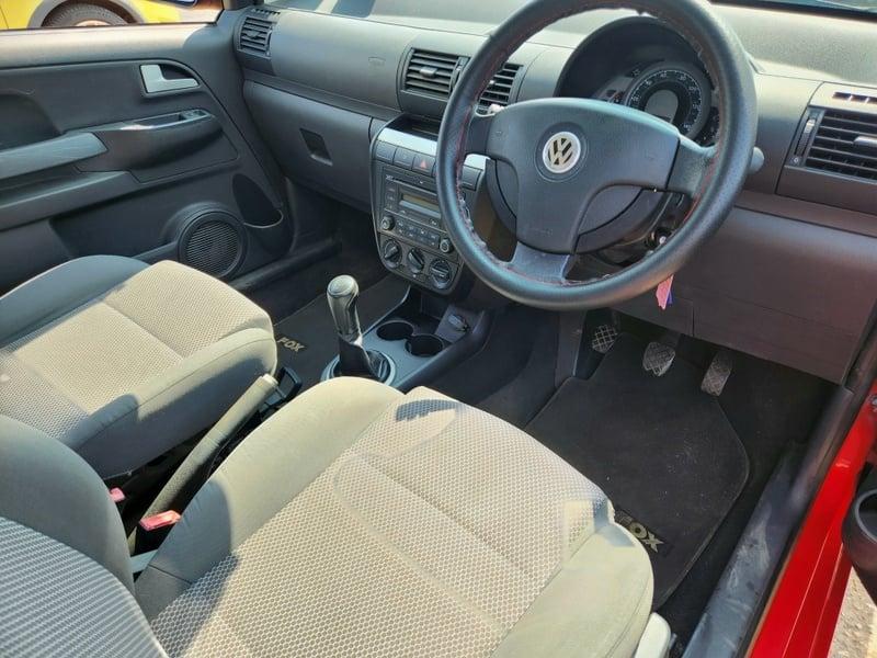 The front seats, steering wheel, and controls on a red Volkswagen Fox, viewed from the right side.