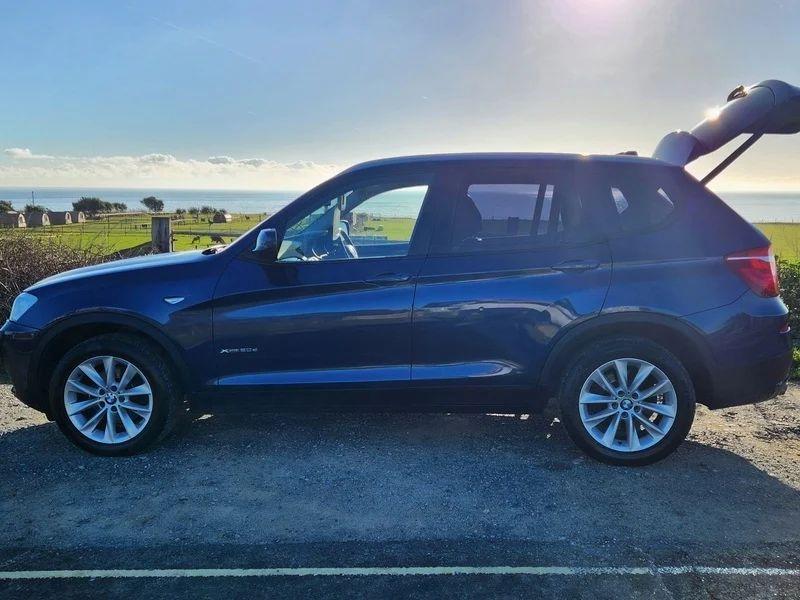 A deepsea blue BMW X3 viewed from the passenger side