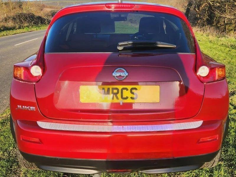 A cayenne red Nissan Juke Acente viewed from behind