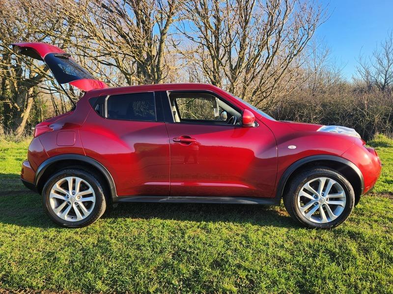 A red Nissan Juke Acenta viewed from the driver side