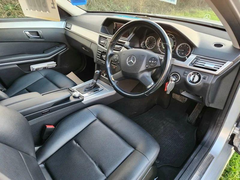 The steering wheel and controls of a  silver Mercedes viewed from the driver seat