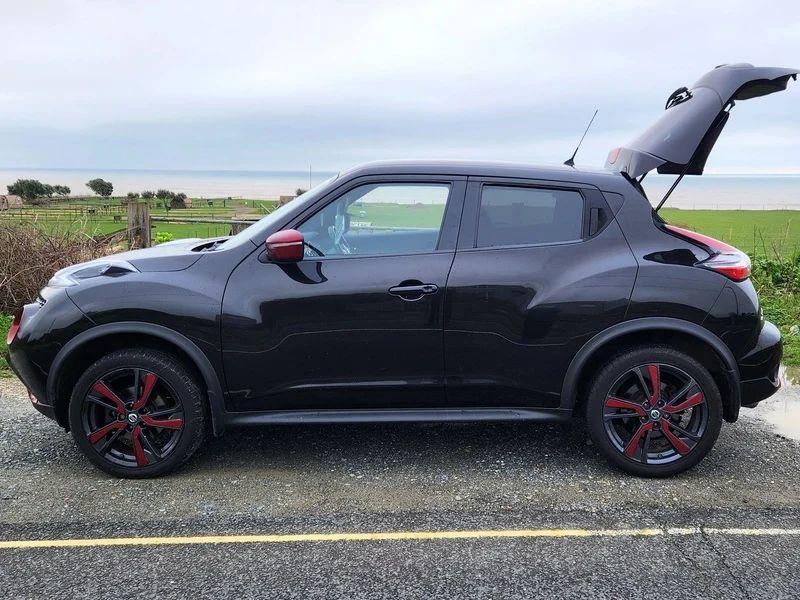 A black Nissan Qashqai, with red reliefs, viewed from the passenger side