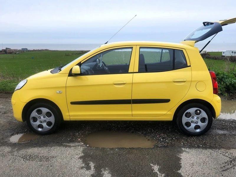 A yellow KIA Picanto viewed from the passenger side