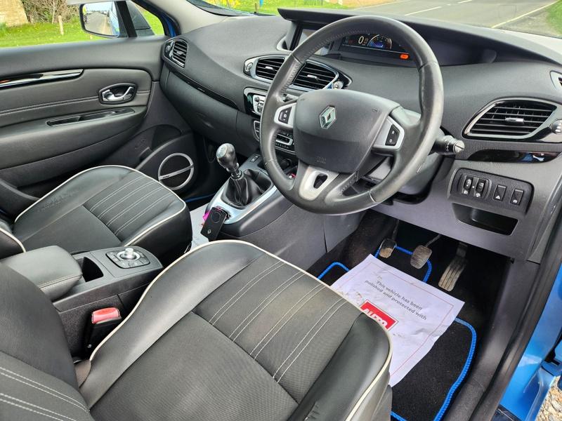 The steering controls of a blue Renault Scenic viewed from above the driver seat