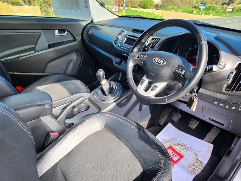 The steering controls of a silver Kia Sportage 2 viewed from above the driver seat