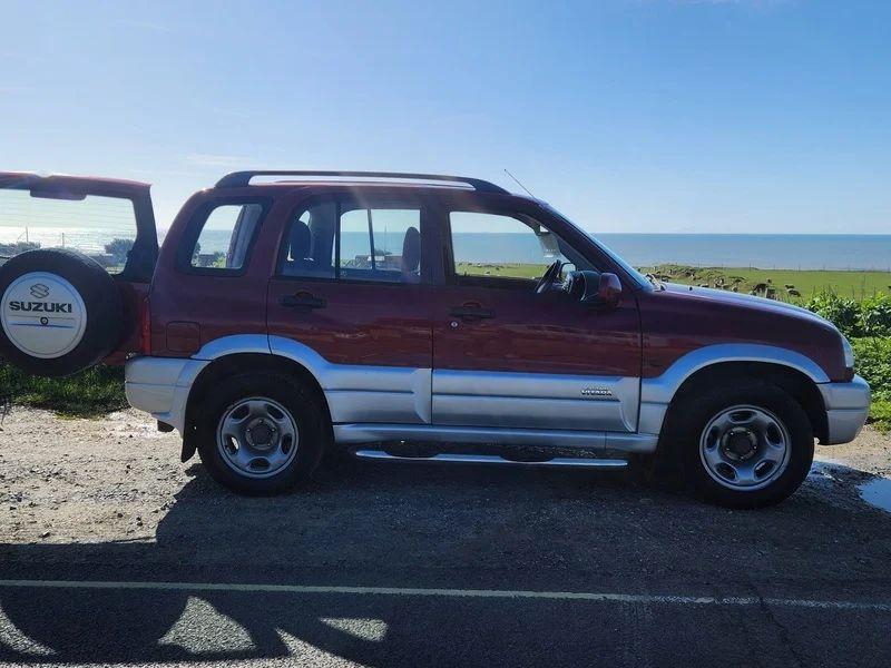 A red Suzuki Grand Vitara viewed from the driver side