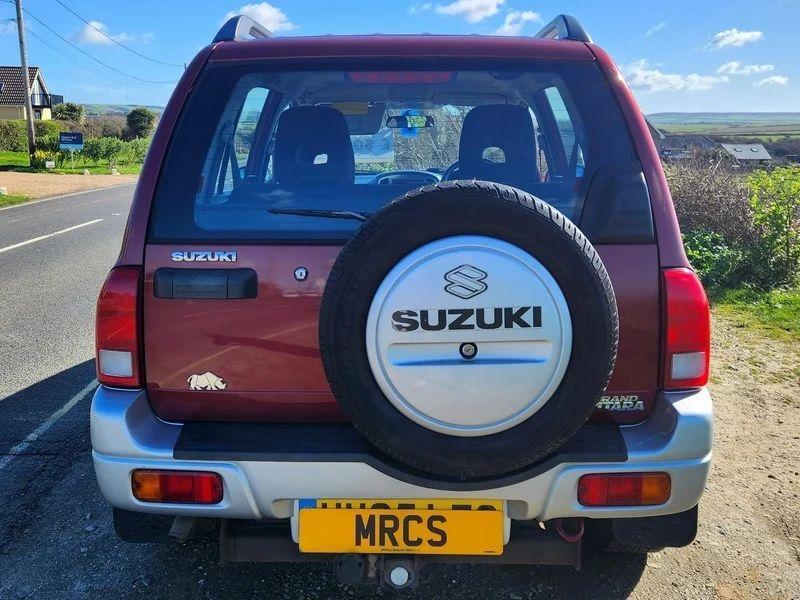 A red Suzuki Grand Vitara viewed from the back
