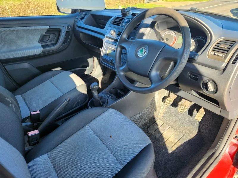 The steering controls of a red Skoda Fabia HTP 1 viewed from above the driver seat