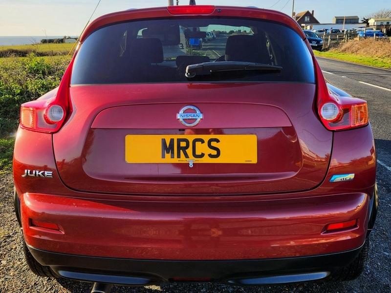 A red Nissan Juke Acenta viewed from the back