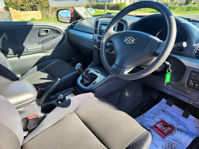 The steering controls of a red Suzuki Grand Vitara viewed from above the driver seat