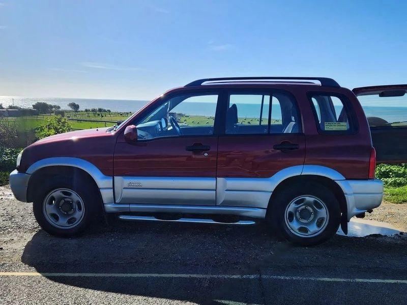 A red Suzuki Grand Vitara viewed from the passenger side