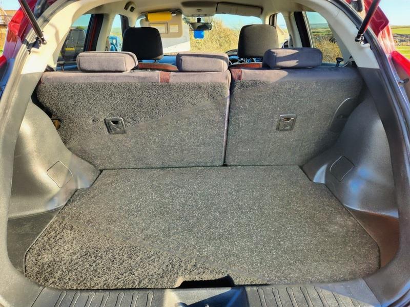 The open boot of a red Nissan Juke Acenta viewed from the back