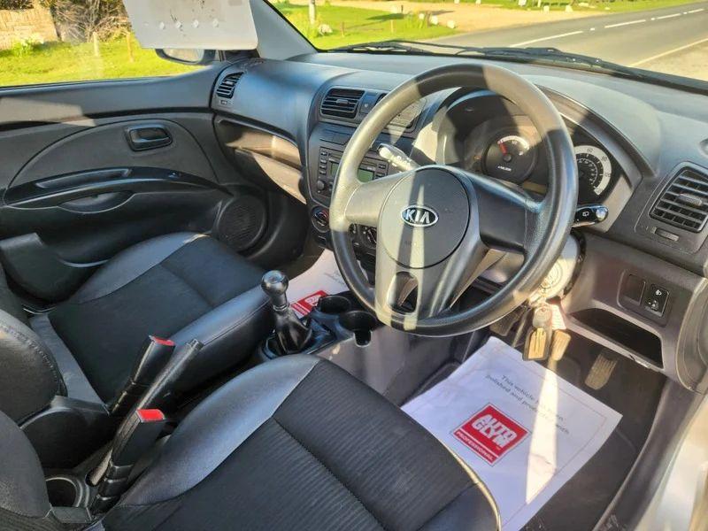 The steering controls of a sparkling silver metallic Kia Picanto viewed from above the driver seat