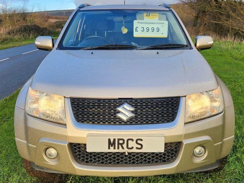 A Suzuki Grand Vitara in Mars Gold Metallic, viewed from the front.