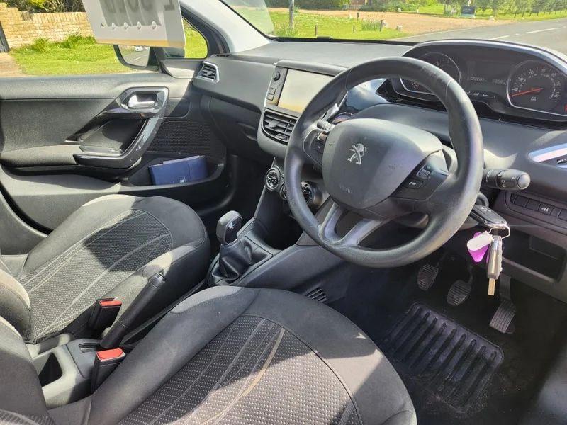 The steering controls of a Peugeot 208 in Rose Pink Quartz Metallic viewed from above the driver seat