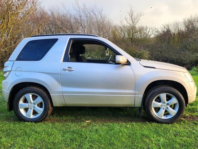 A Suzuki Grand Vitara in Mars Gold Metallic, viewed from the driver side.