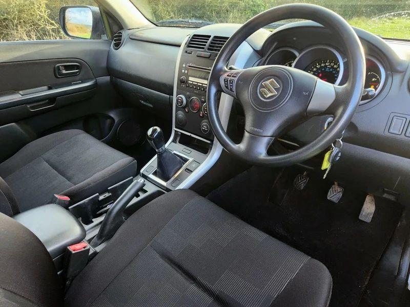 The steering controls of a Suzuki Grand Vitara in Mars Gold Metallic, viewed from above the driver seat.