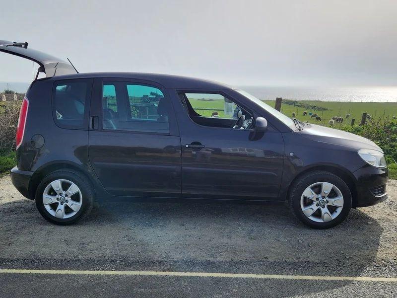 A Skoda Roomster in Jet Black Metallic viewed from the driver side