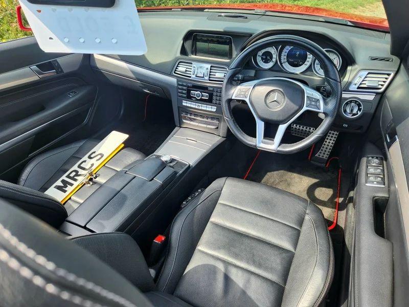 The steering controls of a red Mercedes viewed from above the driver seat
