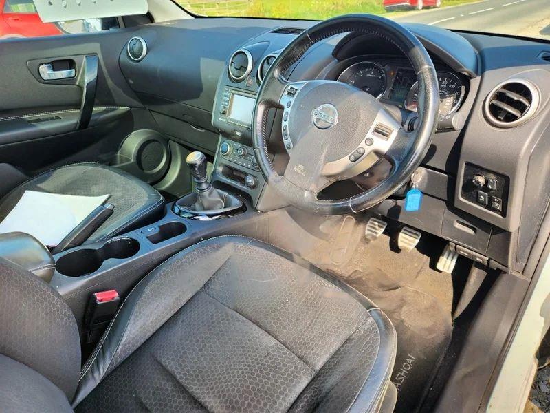 The steering controls of a red Qashqai Acenta viewed from above the driver seat